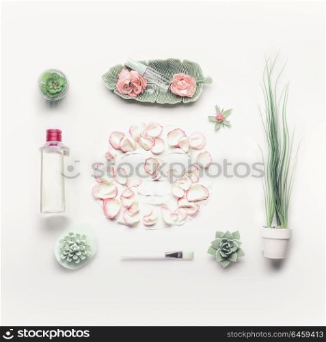 Cosmetic setting for facial skin care with sheet mask , pink roses and roses water, essence or toner on white background, top view, place for text. Beauty and nature herbal cosmetic concept