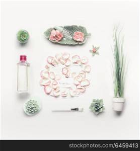 Cosmetic setting for facial skin care with sheet mask , pink roses and roses water, essence or toner on white background, top view, place for text. Beauty and nature herbal cosmetic concept