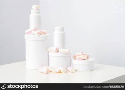 Cosmetic skincare packaging. Beauty product on white background. White jars with marshmallows on the white table. Cosmetic skincare packaging. Beauty product on white background. White jars with marshmallows on the white table.