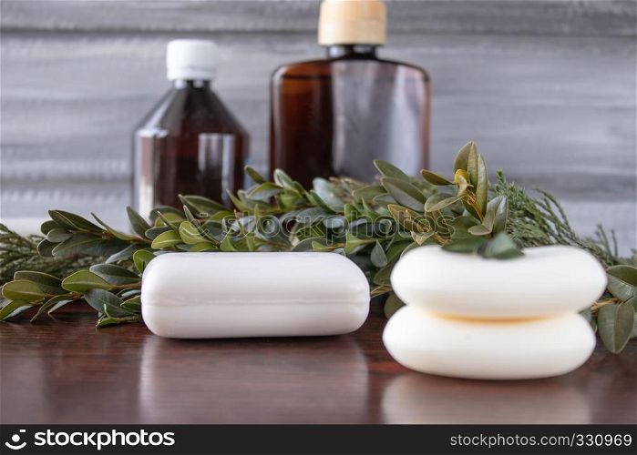 Cosmetic soap in the foreground, dark cans of essential oil on a gray background.. Cosmetic soap, cans of essential oil on a gray background.