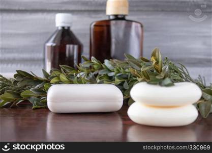 Cosmetic soap in the foreground, dark cans of essential oil on a gray background.. Cosmetic soap, cans of essential oil on a gray background.