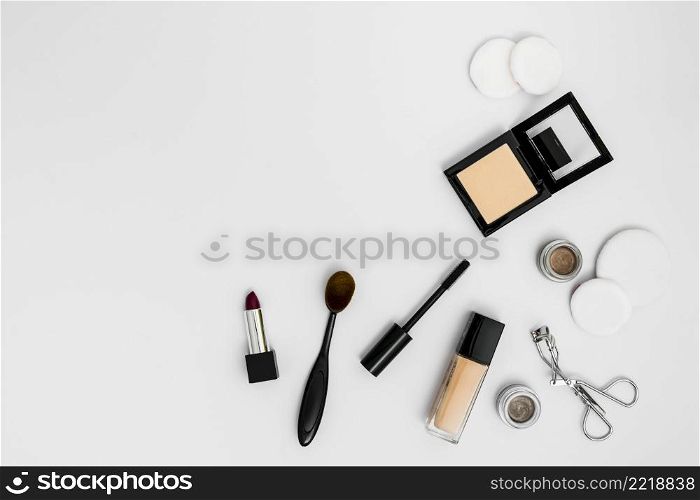 cosmetic sponges compact powder foundation lipstick eyeshadow eyelash curler brushes white background