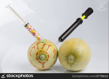 Cosmetic treatment for Female breasts metaphor: melons with perforation lines while air pumped by bicycle pump and injected by a syringe with pillsmeaning cosmetic and health treatment