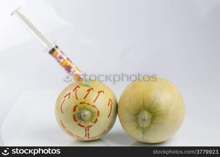 Cosmetic treatment for Female breasts metaphor: melons with perforation lines whileand injected by a syringe with pillsmeaning cosmetic and health treatment