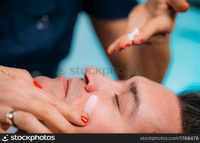 Cosmetic Treatments for Men. Middle Age Man in Beauty Salon Getting Treatment. Cosmetician Applying Cream on Man&rsquo;s Face. . Cosmetic Treatments for Men. Cosmetician Applying Cream on Man&rsquo;s Face. Middle Age Man in Beauty Salon
