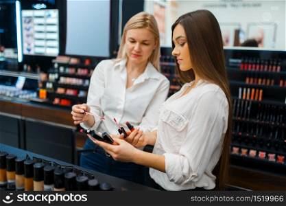 Cosmetician advises woman at the showcase in cosmetics store. Luxury beauty shop salon, female customer and beautician in fashion market. Cosmetician advises woman in cosmetics store