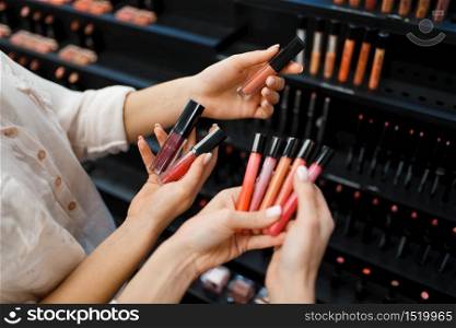 Cosmetician and woman holds nail varnish at the showcase in cosmetics store. Luxury beauty shop salon, female customer and beautician in fashion market. Cosmetician and woman holds nail varnish in store