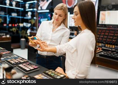 Cosmetician at the counter and woman in cosmetics store. Luxury beauty shop salon, female customer and beautician in fashion store. Cosmetician at counter and woman, cosmetics store