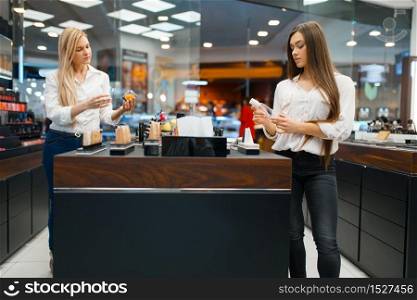 Cosmetician at the counter and woman in cosmetics store. Luxury beauty shop salon, female customer and beautician in fashion market. Cosmetician at counter and woman, cosmetics store