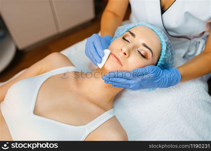 Cosmetician cleans facial skin to female patient. Rejuvenation procedure in beautician salon. Doctor and woman, cosmetic surgery against wrinkles and aging