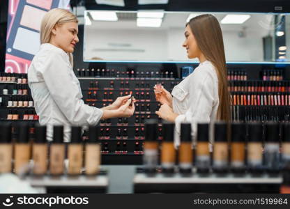 Cosmetician helps woman at the showcase in cosmetics store. Luxury beauty shop salon, female customer and beautician in fashion market. Cosmetician helps woman in cosmetics store