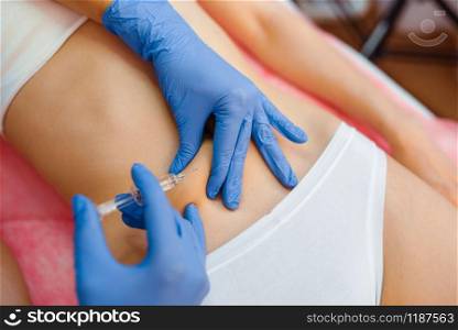 Cosmetician in gloves gives botox injection in the stomach to female patient on treatment table. Rejuvenation procedure in beautician salon. Doctor and woman, cosmetic surgery against wrinkles