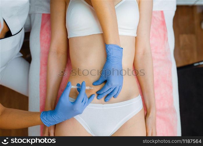 Cosmetician in gloves gives botox injection in the stomach to female patient on treatment table. Rejuvenation procedure in beautician salon. Doctor and woman, cosmetic surgery against wrinkles. Cosmetician gives botox injection in the stomach