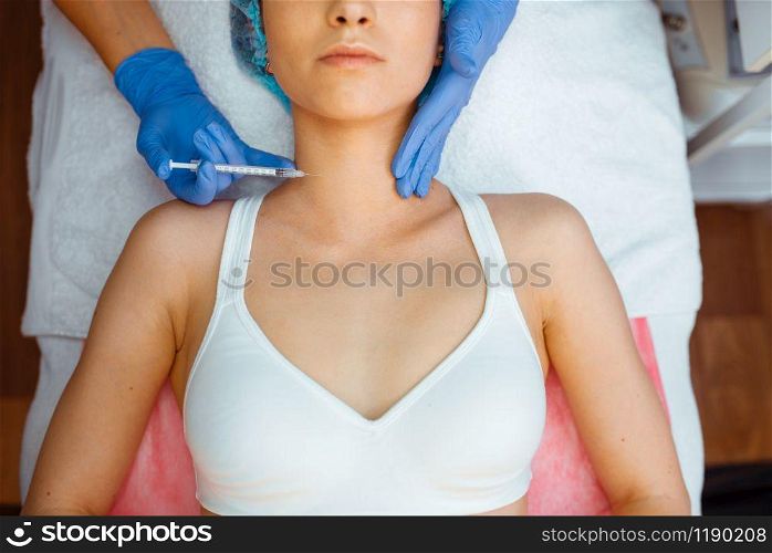Cosmetician in gloves gives botox injection to female patient on treatment table, top view. Rejuvenation procedure in beautician salon. Doctor and woman, cosmetic surgery against wrinkles. Cosmetician gives botox injection against wrinkles