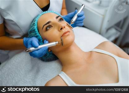 Cosmetician smoothes face of female patient after botox injections. Rejuvenation procedure in beautician salon. Doctor and woman, cosmetic surgery against wrinkles and aging. Cosmetician smoothes face of female patient
