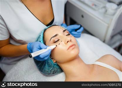 Cosmetician with marker puts dotted lines on female patient face, botox injections preparation. Rejuvenation procedure in beautician salon. Cosmetic surgery against wrinkles and aging