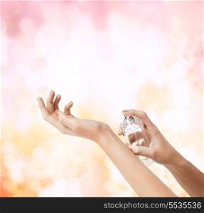 cosmetics, body parts and beauty concept - close up of woman hands spraying perfume