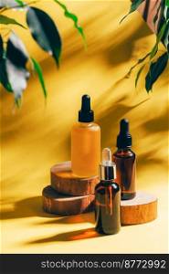 Cosmetics for face or body for SPA procedures. Aromatherapy essential oil, gel, serum on various wooden podiums on trendy yellow orange background sunny hard shadows. Cosmetics for face body for SPA procedures. Aromatherapy essential oil gel serum on wooden podiums yellow background