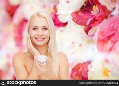 cosmetics, health and beauty concept - beautiful woman applying cream on her skin