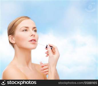 cosmetics, health and beauty concept - beautiful woman with pink lipgloss