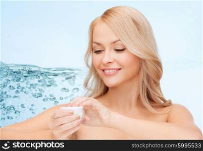 cosmetics, health and beauty concept - woman applying moisturizing cream to her face skin