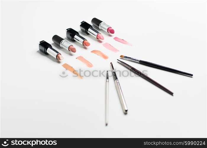 cosmetics, makeup and beauty concept - close up of lipsticks range with brushes