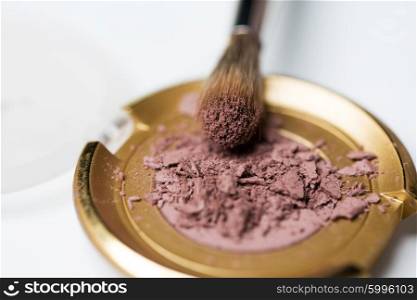 cosmetics, makeup and beauty concept - close up of makeup brush and eyeshadow