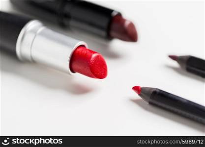 cosmetics, makeup and beauty concept - close up of two open lipsticks and lip pencils