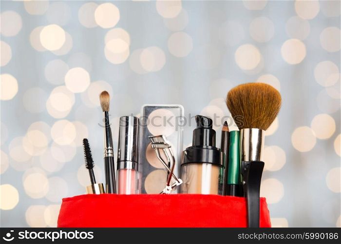cosmetics, makeup, holidays and beauty concept - close up of cosmetic bag with makeup stuff over lights background