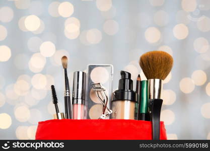 cosmetics, makeup, holidays and beauty concept - close up of cosmetic bag with makeup stuff over lights background