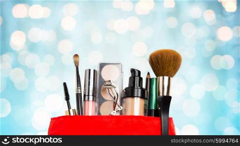 cosmetics, makeup, holidays and beauty concept - close up of cosmetic bag with makeup stuff over blue lights background
