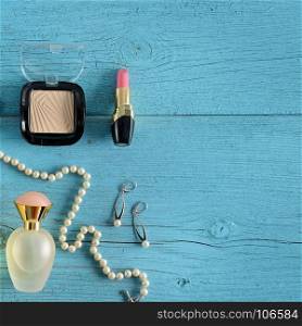 Cosmetics, perfumes and jewelry made of pearls on an old wooden background of blue color. Flat lay, top view. Free space for text.