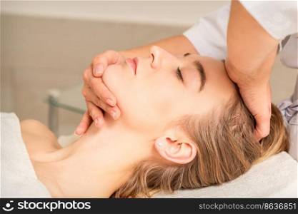 Cosmetologist hands doing facial massage on forehead and chin of young female at spa salon. Cosmetologist hands doing facial massage on forehead and chin of young female at spa salon.