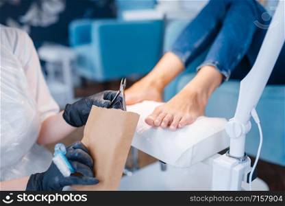 Cosmetologist salon, pedicure, clipping procedure. Nail care treatment for female client in beauty shop, doctor in gloves works with customer toenails