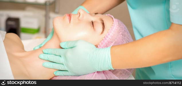 Cosmetologist with gloved hands applies a moisturizing mask with peeling cream on the female face. Facial cosmetology treatment. Procedures for facial care. Cosmetologist with gloved hands applies a moisturizing mask with peeling cream on the female face. Facial cosmetology treatment. Procedures for facial care.