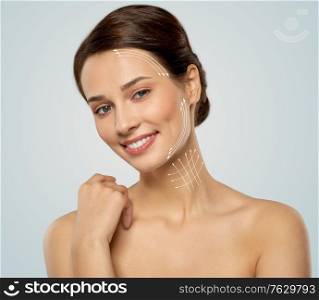 cosmetology, plastic surgery and beauty concept - beautiful smiling young woman face with massage lines over grey background. beautiful young woman face with massage lines