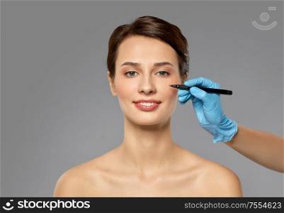 cosmetology, plastic surgery and beauty concept - beautiful young woman and hand with marker over grey background and snow. beautiful young woman and hand with marker