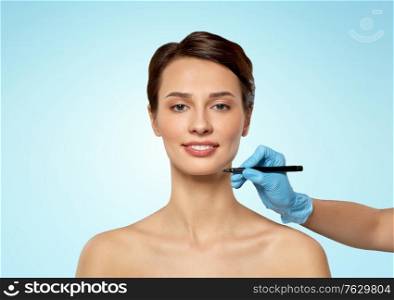 cosmetology, plastic surgery and beauty concept - beautiful young woman and hand with marker over blue background. beautiful young woman and hand with marker