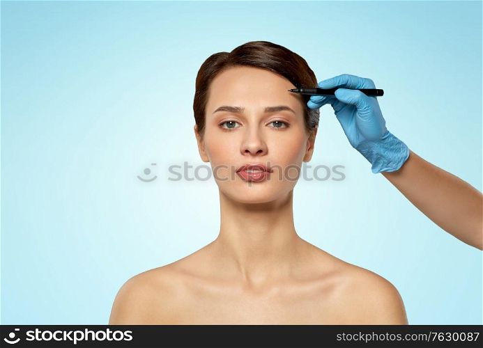 cosmetology, plastic surgery and beauty concept - beautiful young woman and hand with marker over blue background and snow. beautiful young woman and hand with marker
