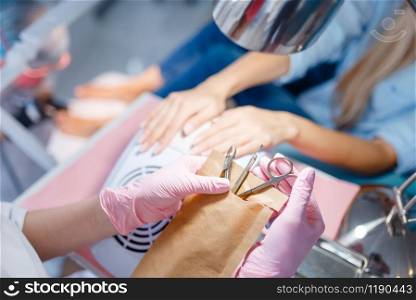 Cosmetology salon, manicure, nails polishing procedure. Hands care treatment for female client in beauty shop, woman at the cosmetologist, master works with fingernails. Cosmetology salon, manicure, polishing procedure