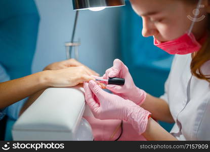 Cosmetology salon, manicure, varnish application procedure. Hands care treatment for female client in beauty shop, woman at the cosmetologist, master works with fingernails. Cosmetology salon, manicure, varnish application