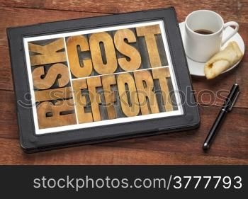 cost, effort, risk - business concept - a word abstract in vintage wood letterpress printing blocks on a digital tablet with cup of coffee