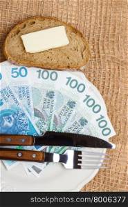 Cost of living, price of eating food budget concept. Polish money on kitchen table, piece of bread on plate