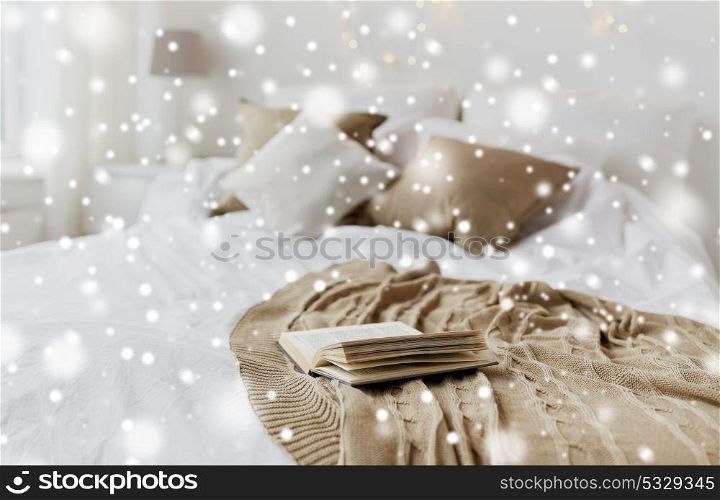 cosy home and winter concept - book on bed in bedroom at christmas over snow. book on bed in bedroom at christmas home