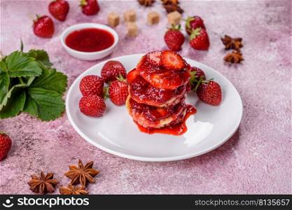 Cotta≥cheese pancake with strawberry jam on a concrete background. Cotta≥cheese pancakes with sliced strawberries and strawberry jam on a plate on a concrete background