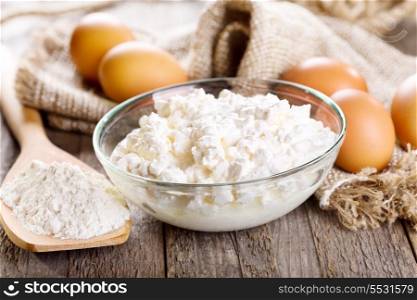 cottage cheese, eggs and flour on wooden table