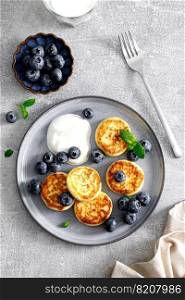 Cottage cheese fritters with fresh blueberry and yogurt for breakfast, view from above