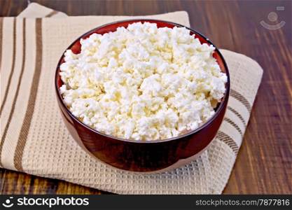 Cottage cheese in a wooden bowl on brown napkin on a wooden boards background