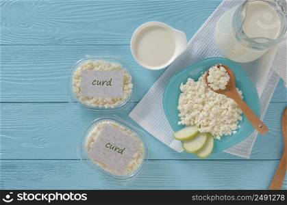 Cottage cheese in plastic packaging and milk on a wooden blue background, top view. healthy eating concept. dairy products on a blue background