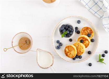 Cottage cheese or curd fritters with honey and fresh blueberry. Healthy diet food, breakfast. Top view.